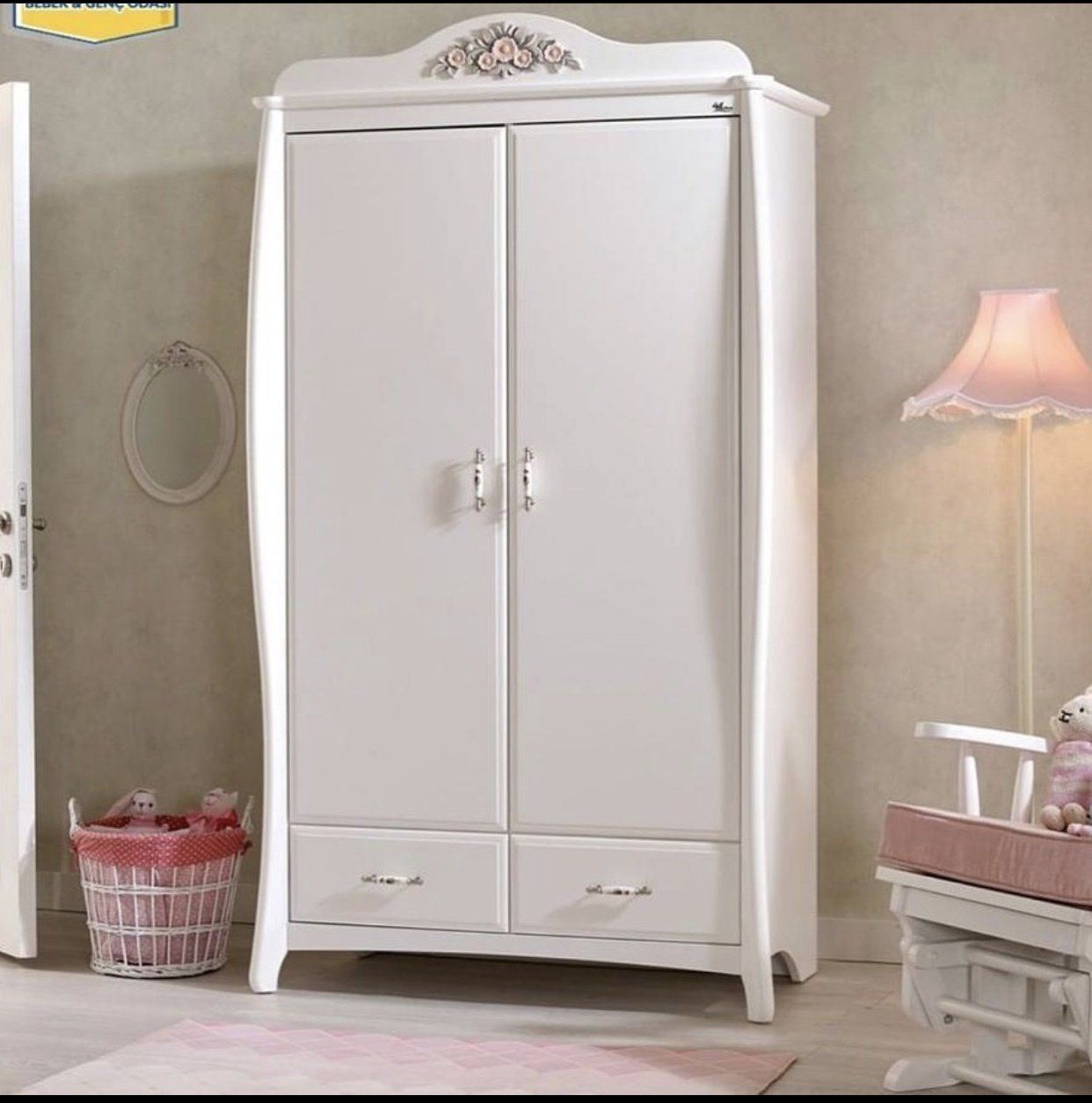 A cream-colored two-door wardrobe with floral motifs on the top, two bottom drawers.